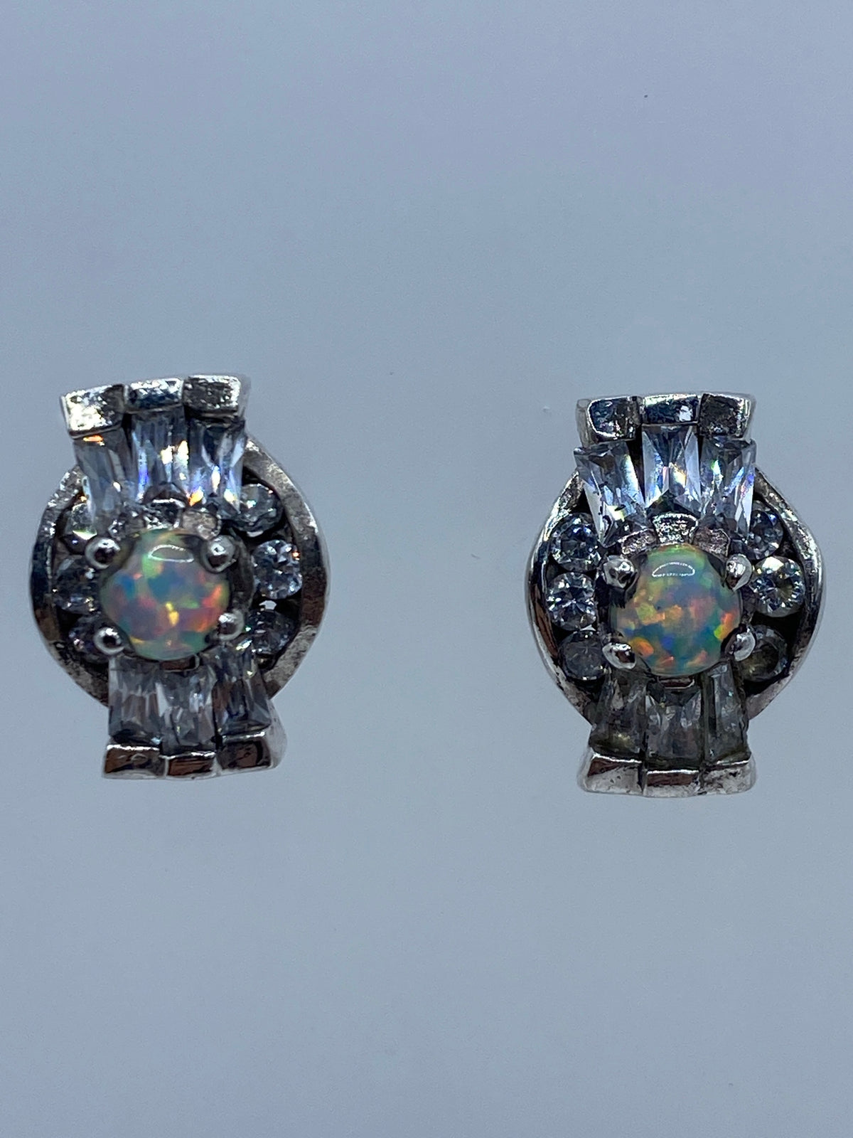 Par de aretes de plata 925 con ópalo de fuego multicolor, vistos de frente en fondo gris