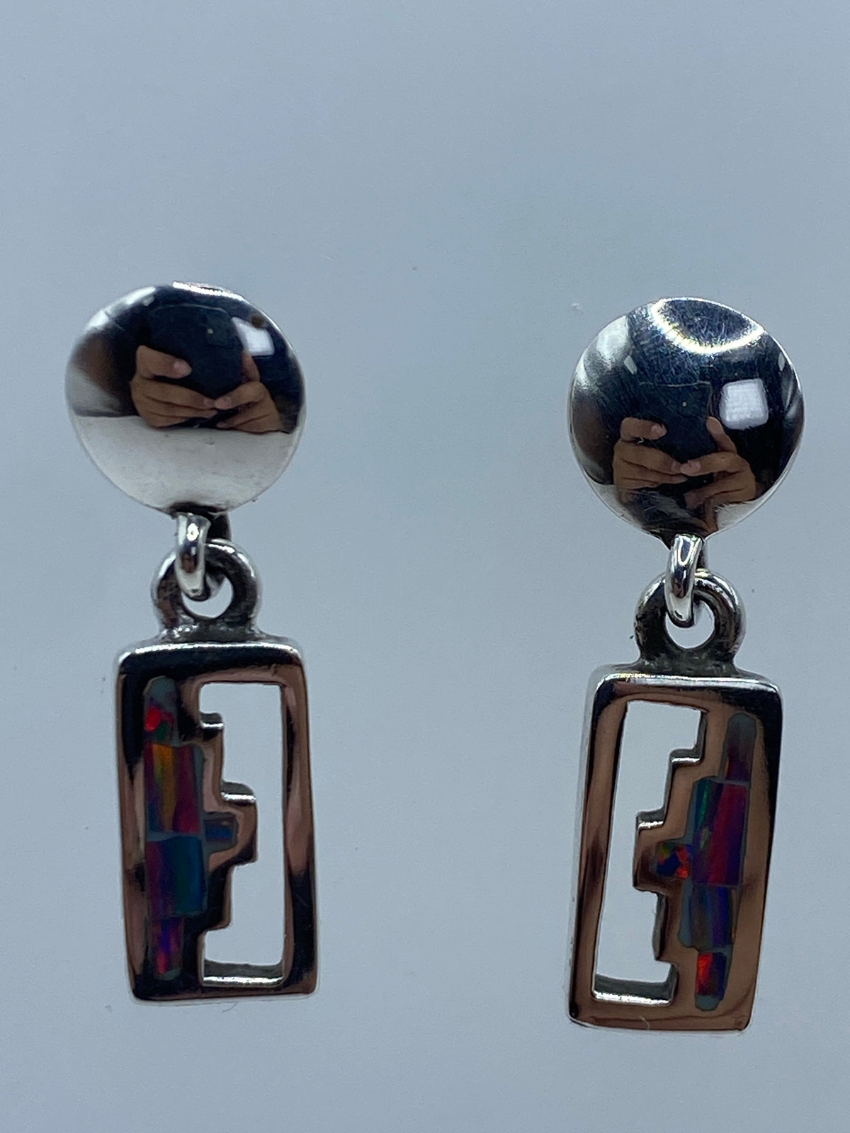 Par de aretes de plata con ópalo de fuego azul, sobre fondo blanco