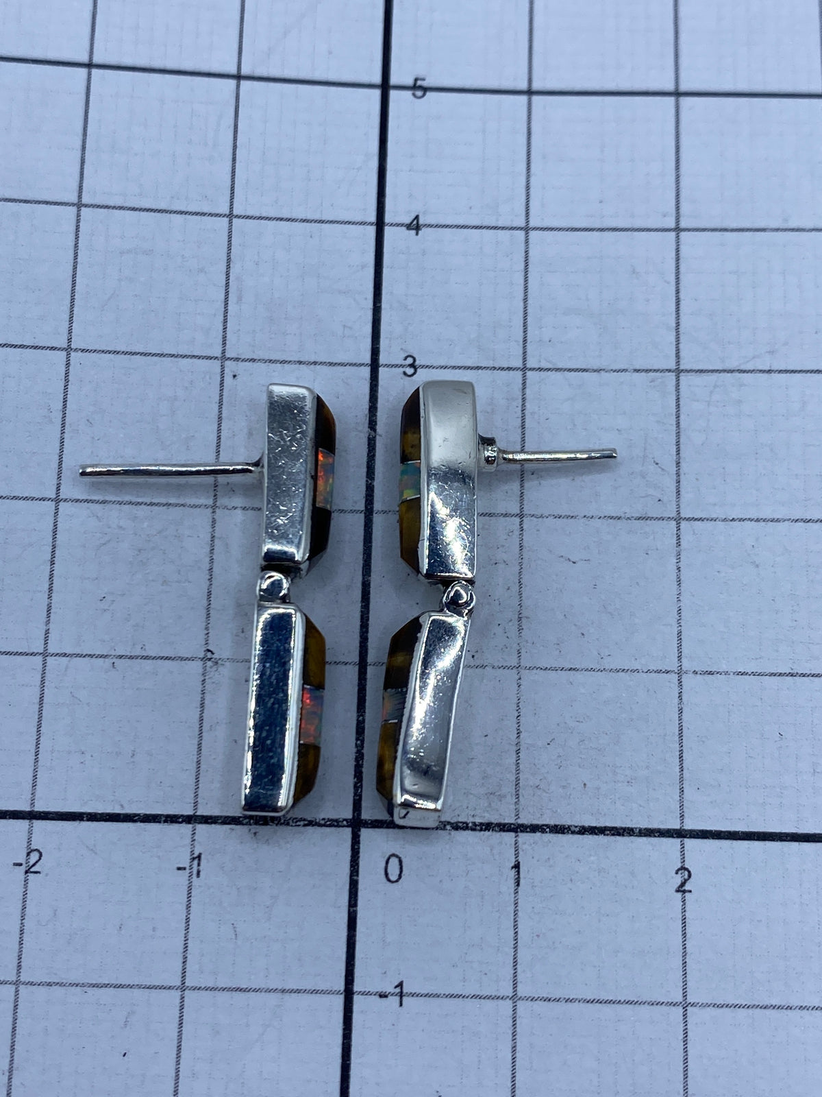 Aretes sobre fondo blanco con poste plateado visible, mostrando la pureza 950 del metal