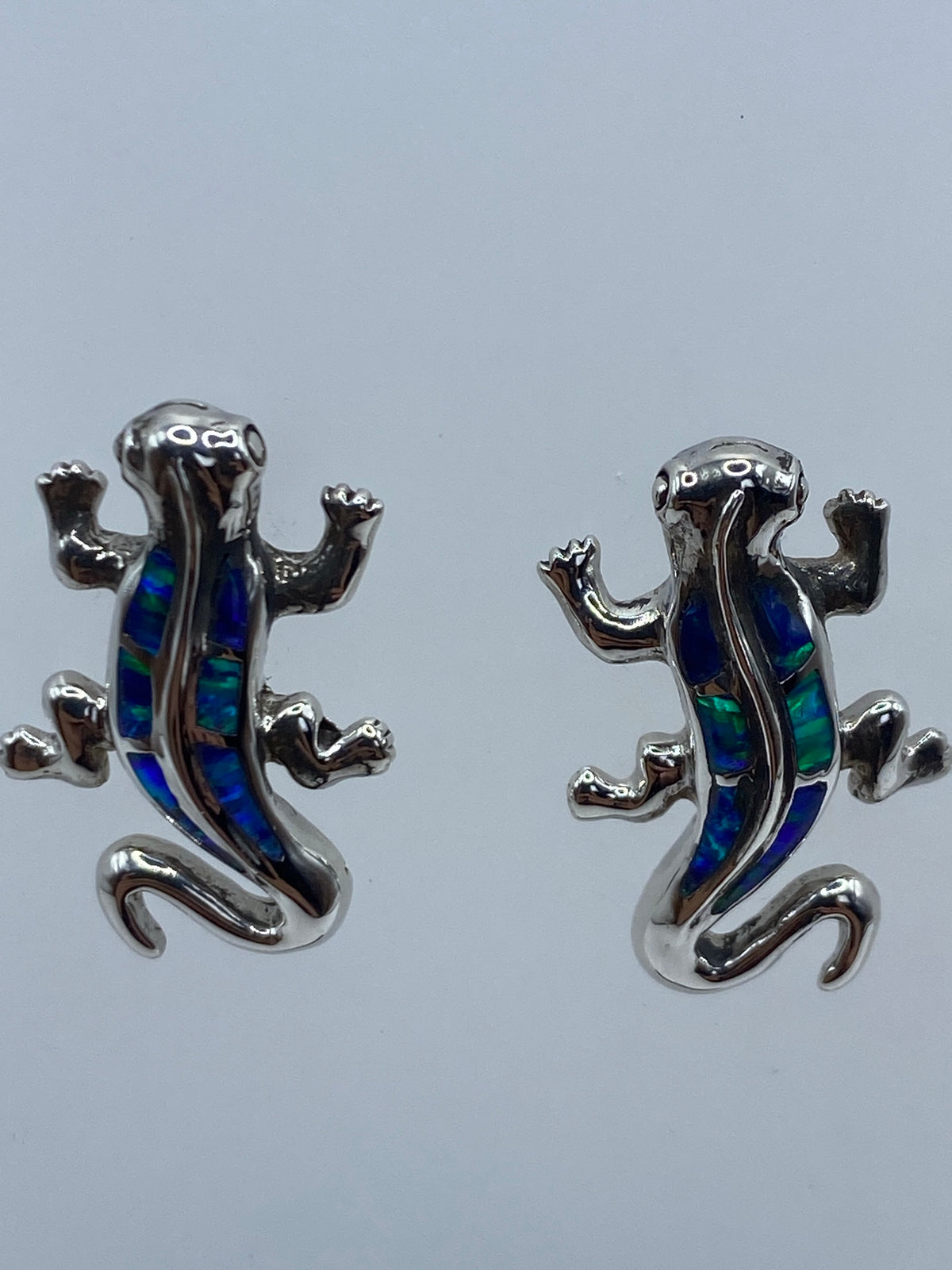 Aretes de plata con ópalo sobre fondo gris mostrando el Quinto