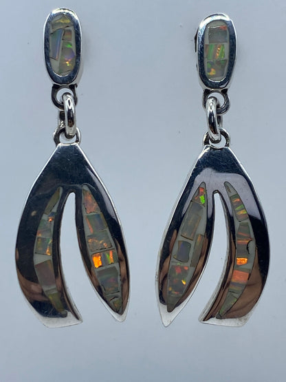 Los dos aretes de ópalo fuego lado a lado, iluminados para destacar los tonos dorados y verdes