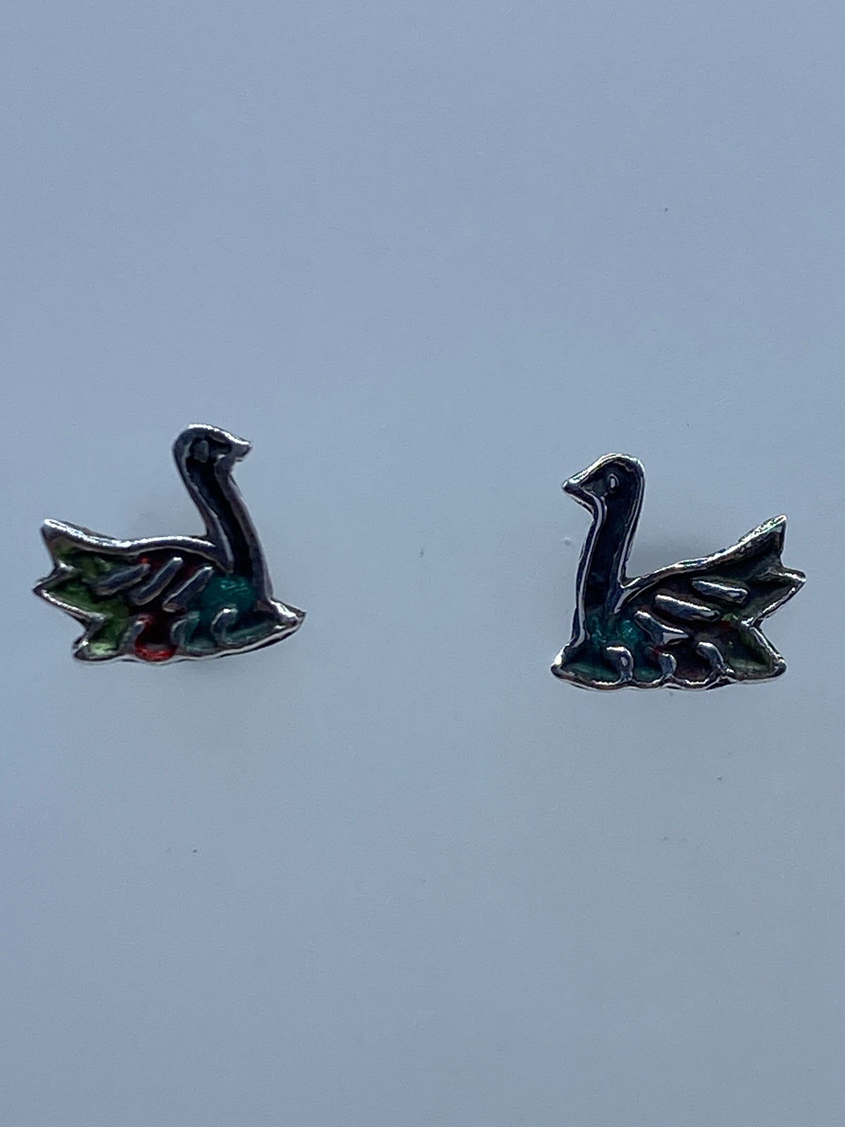 Par de aretes de plata minimalistas vistos de frente sobre fondo gris
