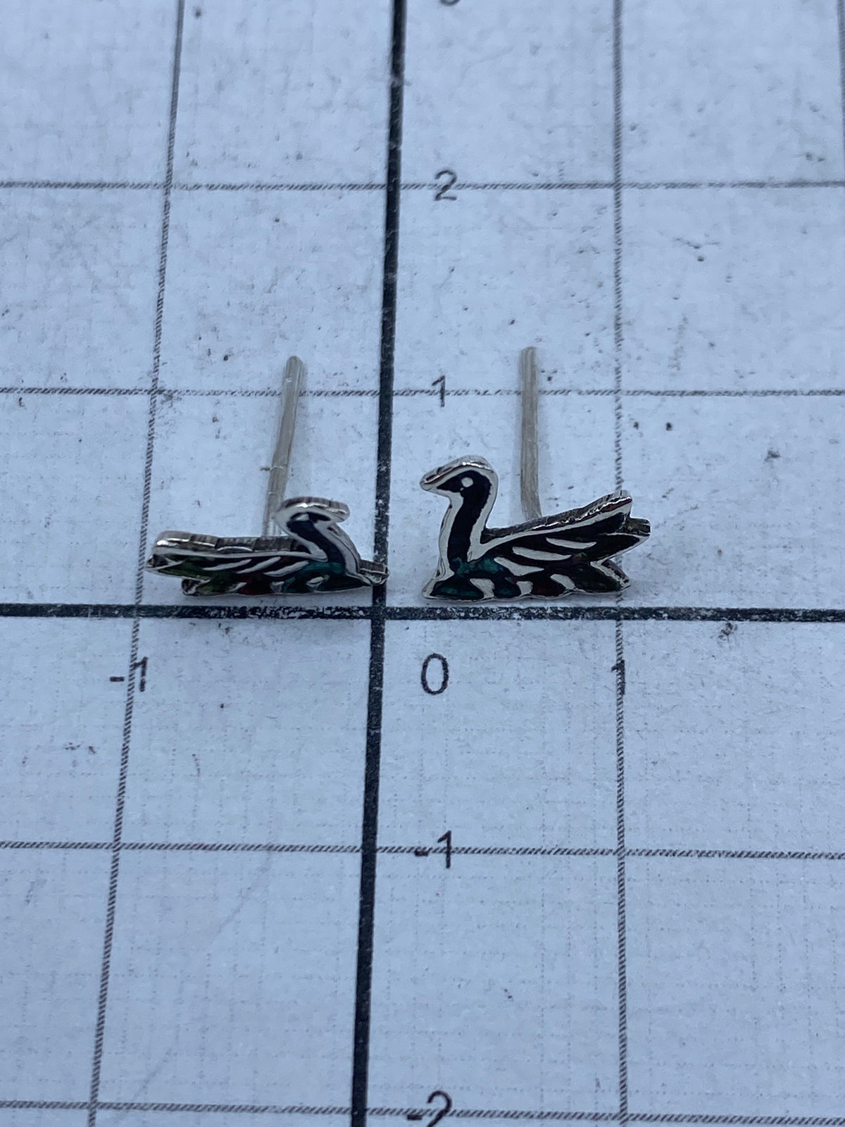 Aretes de plata pura pesados en bascula de joyero mostrando 0.9 gramos