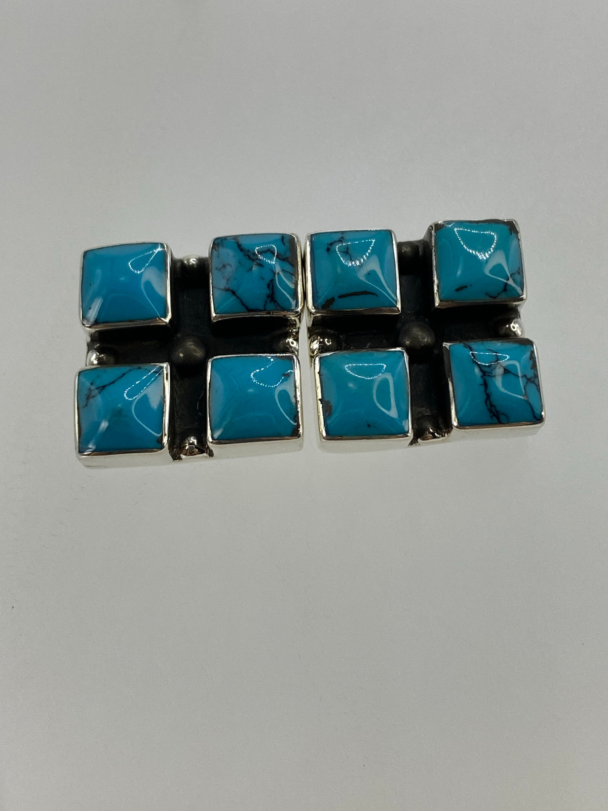 Vista frontal del par de aretes de turquesa azul con cierre de perno de plata