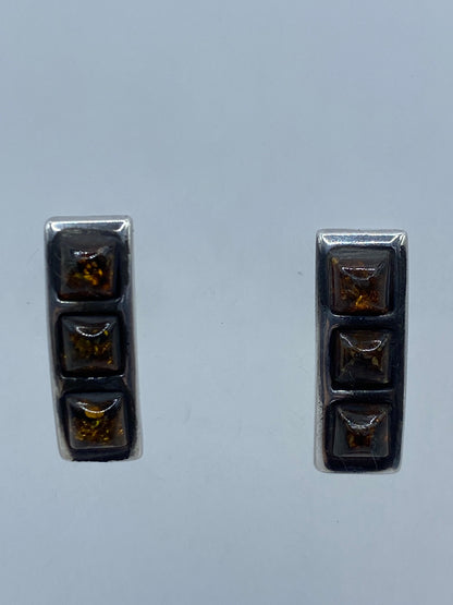 Vista frontal de los aretes de plata 925 con ámbar cálido