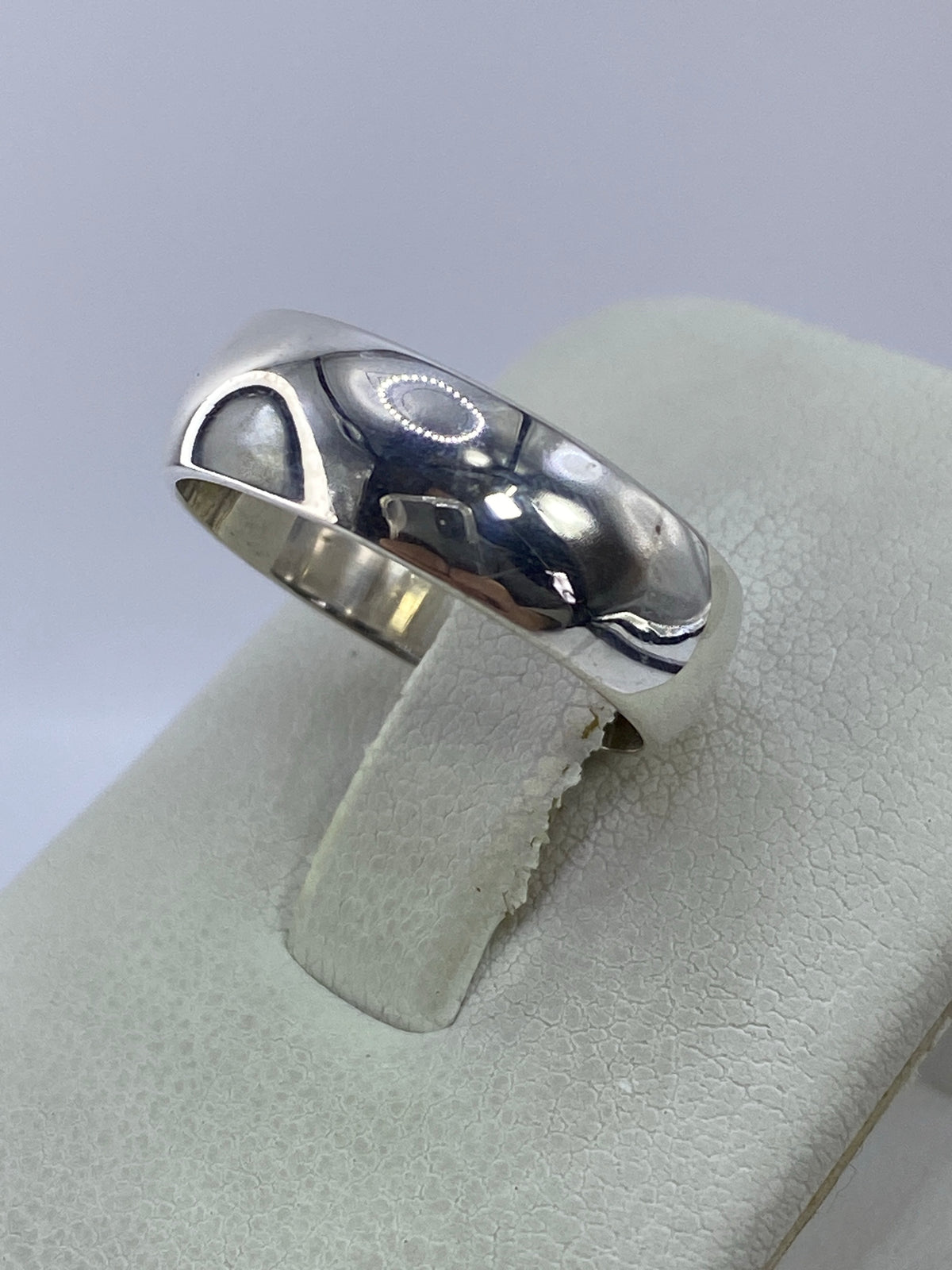 Detalle lateral del anillo de plata — pulido espejo reflejando luz
