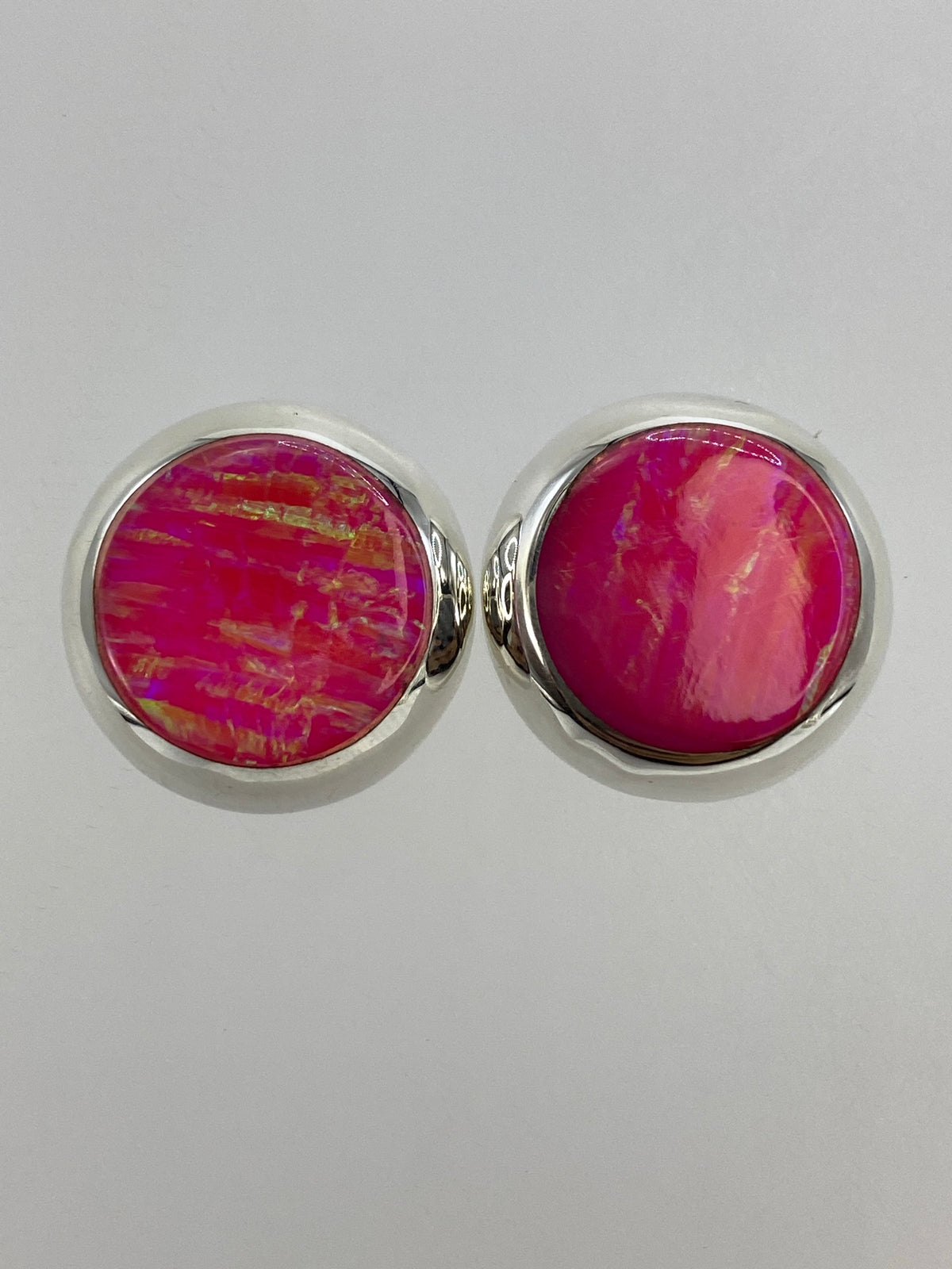 Par de aretes de plata 925 con opalo de fuego rosa engastado, reflejando luz cálida