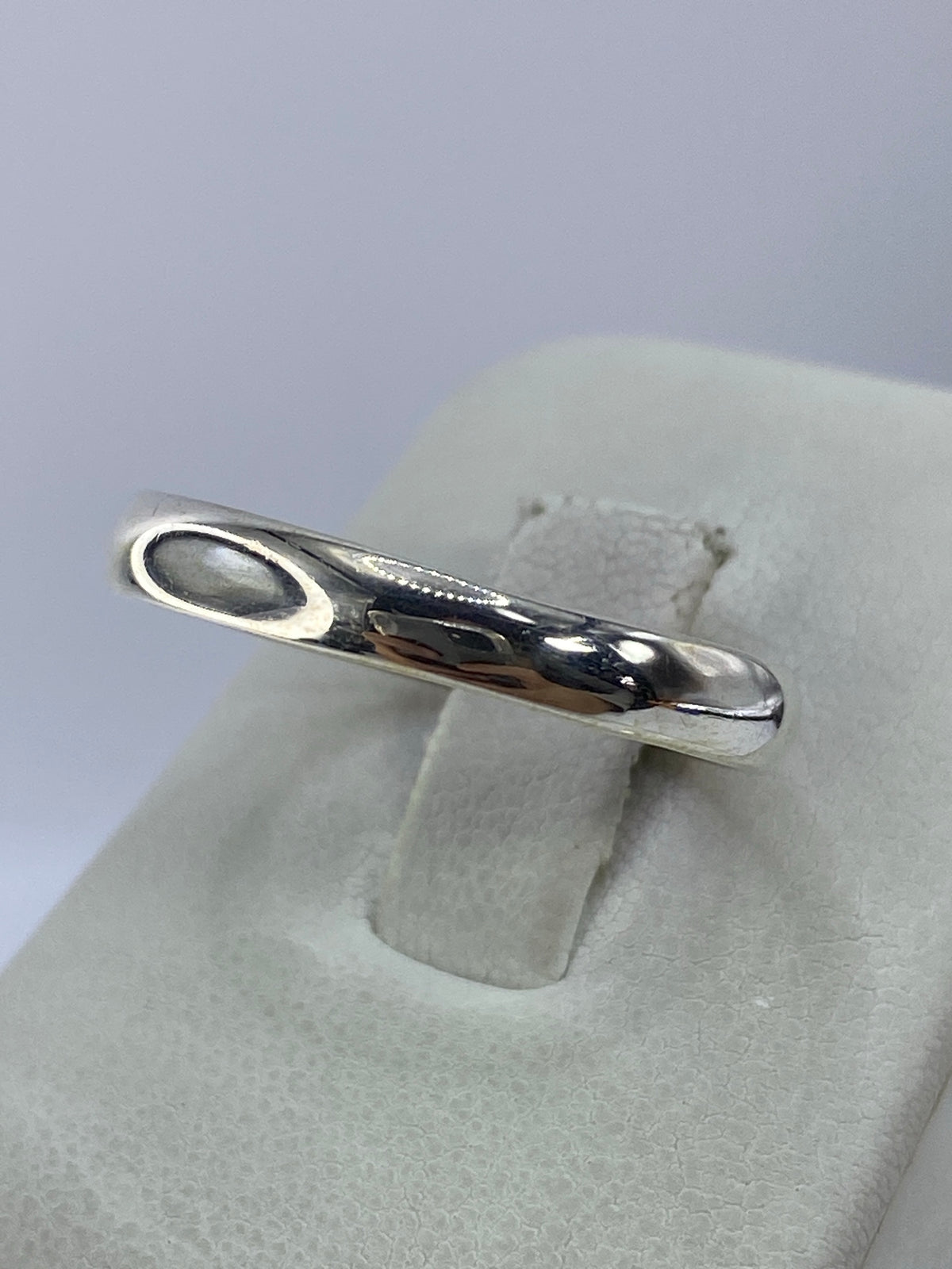 Anillo de plata en diseño minimalista visto de lado, mostrando el acabado pulido