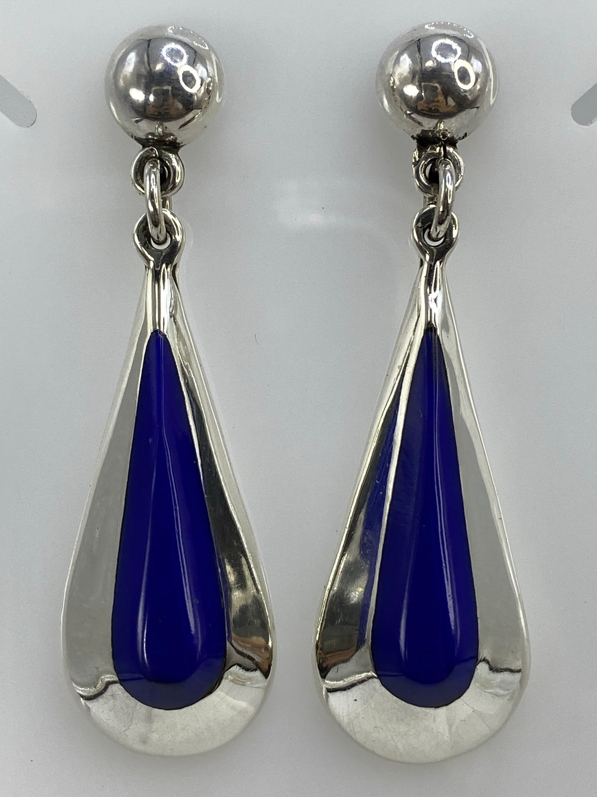 Aretes en la mano mostrando el largo de 6.1 cm y el tono azul profundo