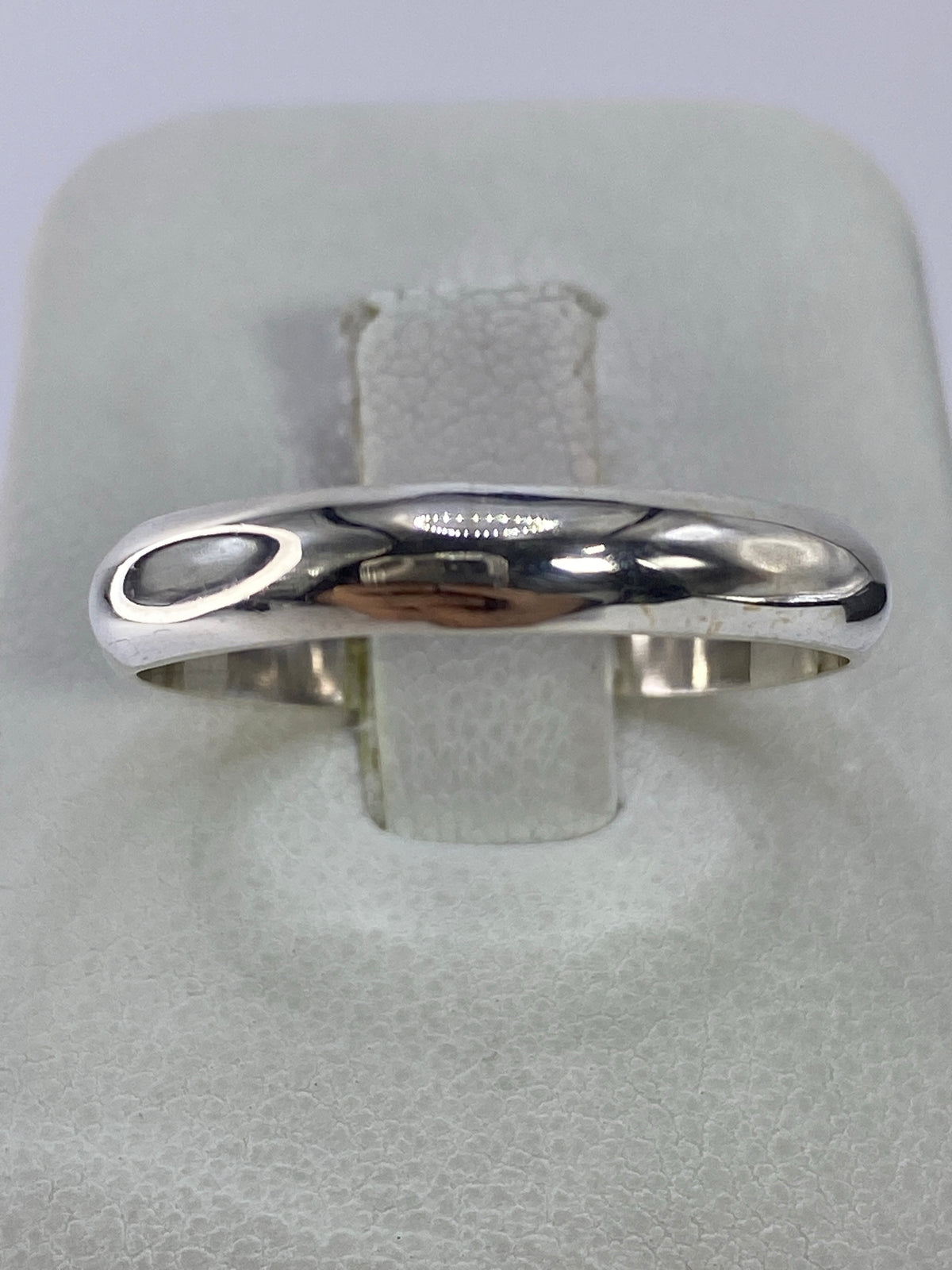 Anillo de plata pulido minimalista en mano de mujer, vista superior