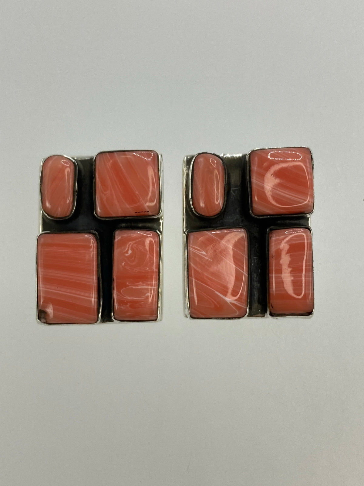 Par de aretes de plata con coral rosa, vista frontal sobre fondo neutro