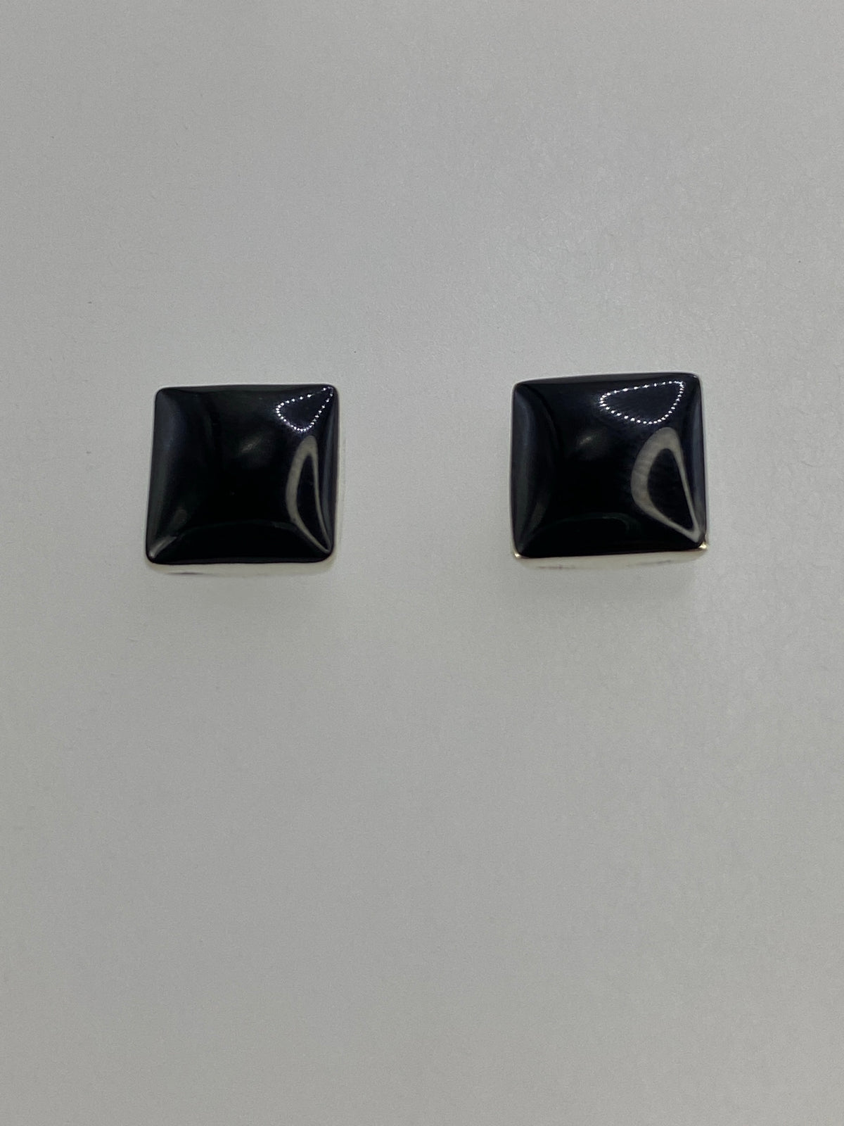 Par de aretes cuadrados de plata 950 con ónix negro engastado, vistos de frente sobre fondo blanco