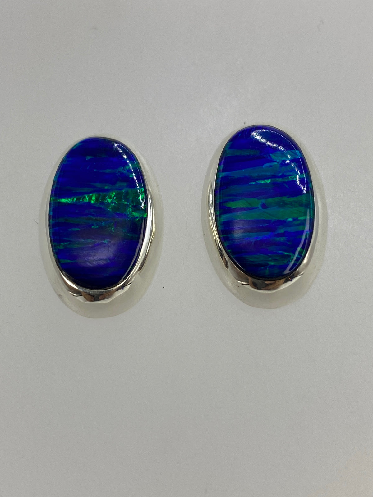 Detalle frontal de los aretes mostrando el color azul y los reflejos del ópalo