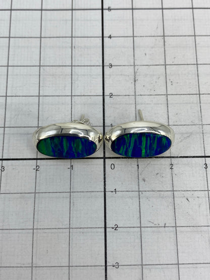 Aretes sobre regla métrica para mostrar tamaño (2 cm largo × 1.5 cm ancho)