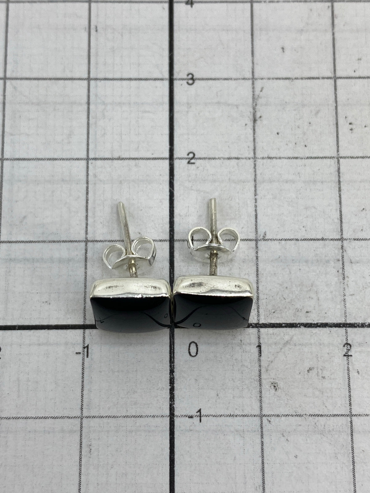 Aretes colocados en la mano mostrando su tamaño minimalista y peso ligero