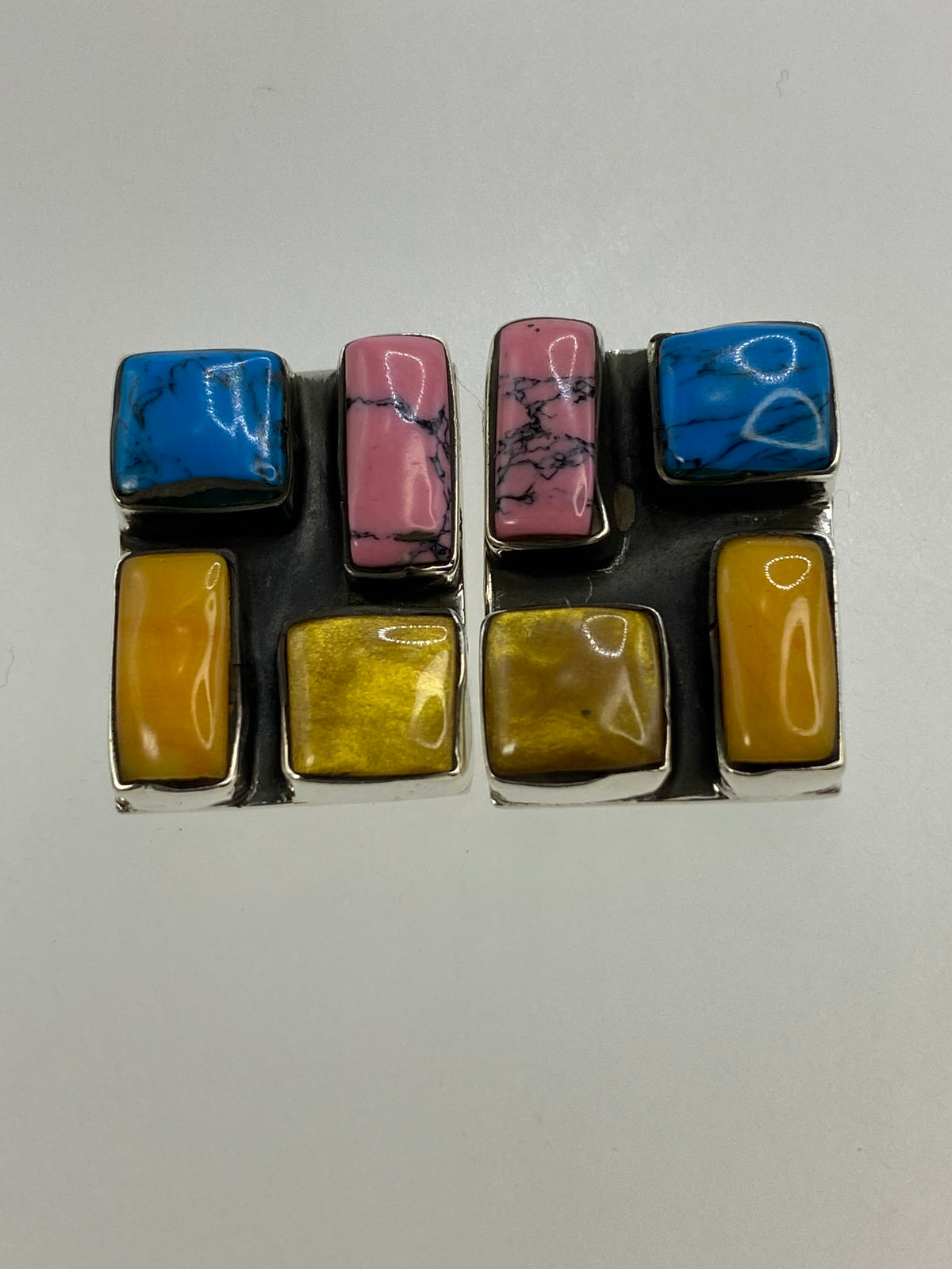 Detalle del engaste de turquesa en tonos azul, rosa y amarillo en los aretes