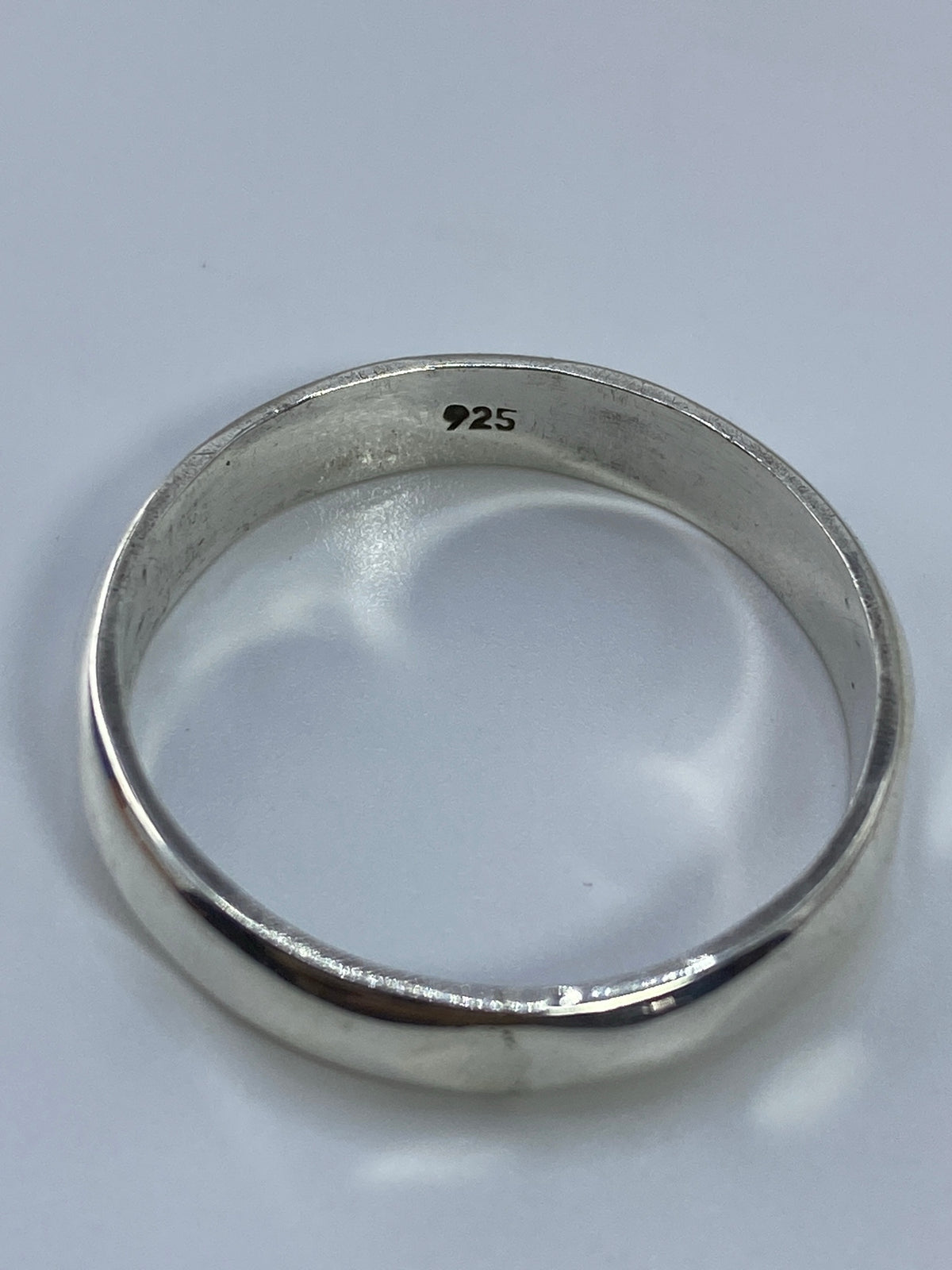 Anillo de banda de plata sobre fondo blanco con peso de 4.55 gramos en báscula