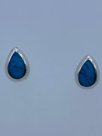Detalle frontal de los aretes mostrando la turquesa engastada y el poste de plata