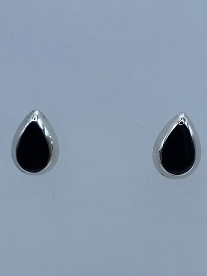 Aretes de plata 925 con ónix negro engastado, vistos de frente sobre fondo azul
