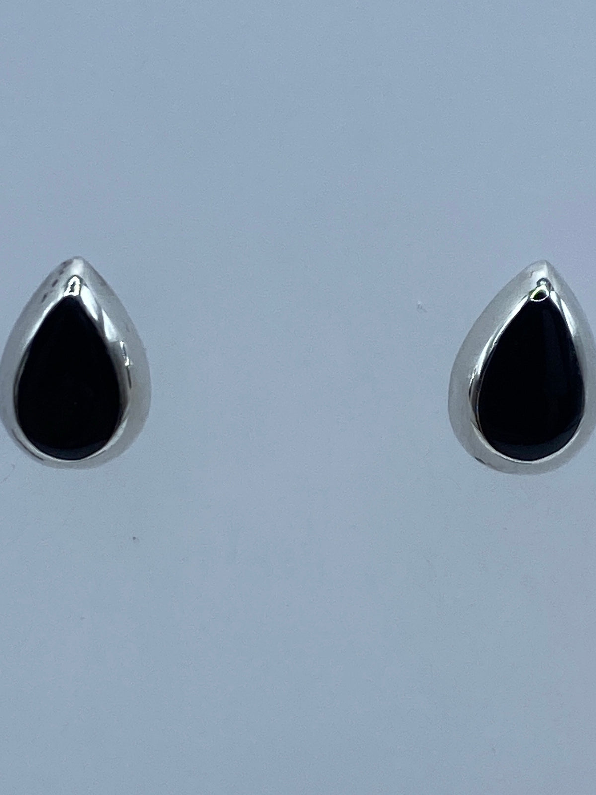 Aretes de plata con ónix negro en escala de medida, mostrando tamaño real de 1.1 cm