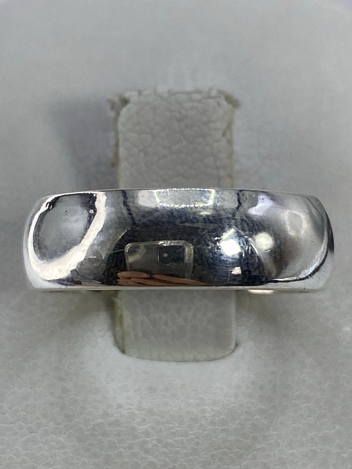 Anillo de plata 925 minimalista pulido en la mano, banda lisa y brillante