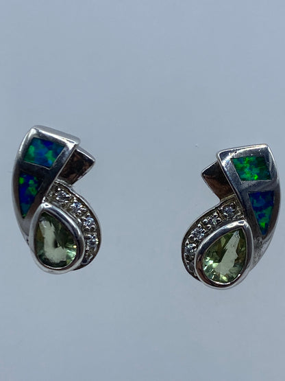 Vista frontal de aretes minimalistas ópalo azul contra fondo gris