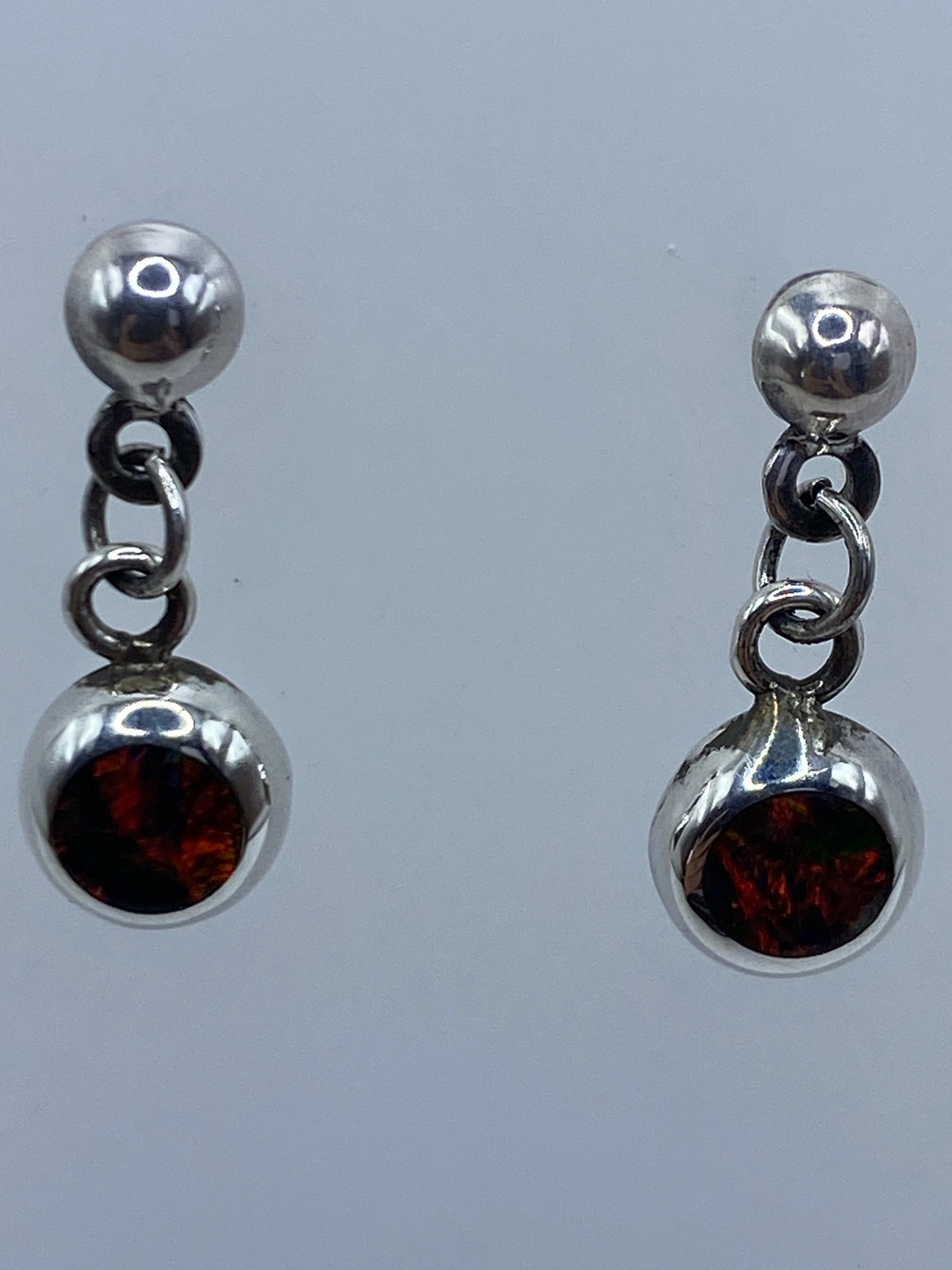 Detalle lateral de aretes de plata con engaste de ópalo de fuego