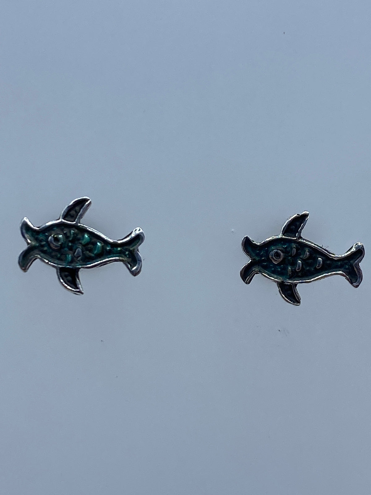 Aretes tortuga marina sobre regla de centímetros mostrando el largo de 1.1 cm