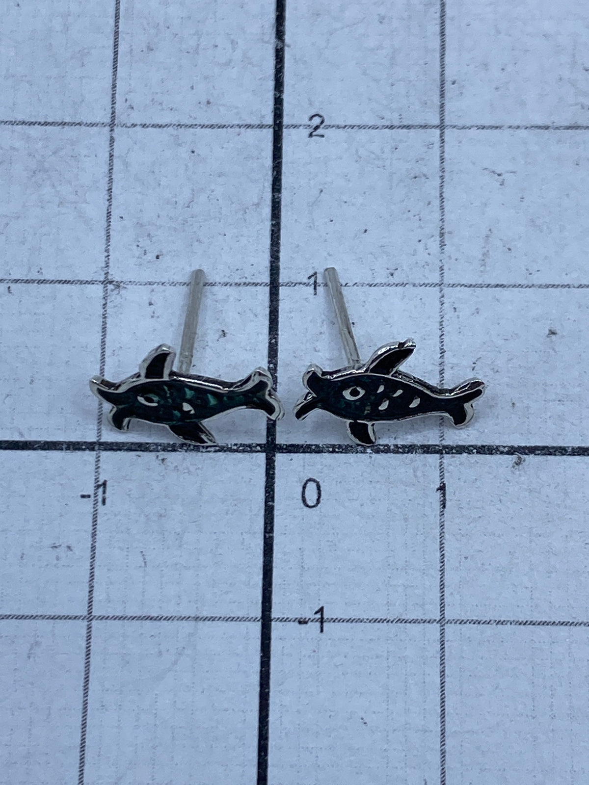 Aretes tortuga colocados sobre fondo blanco con postes de presión visibles