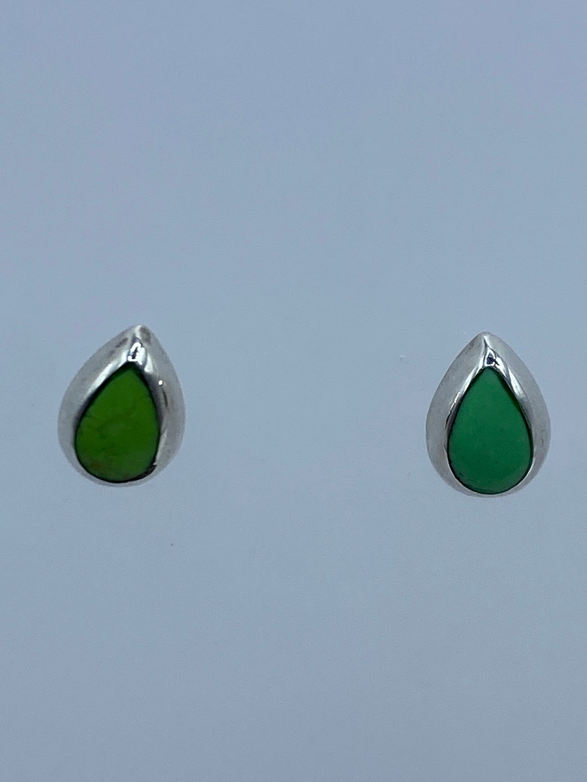 Par de aretes de plata 925 con piedra verde engastada, vista frontal sobre fondo azul
