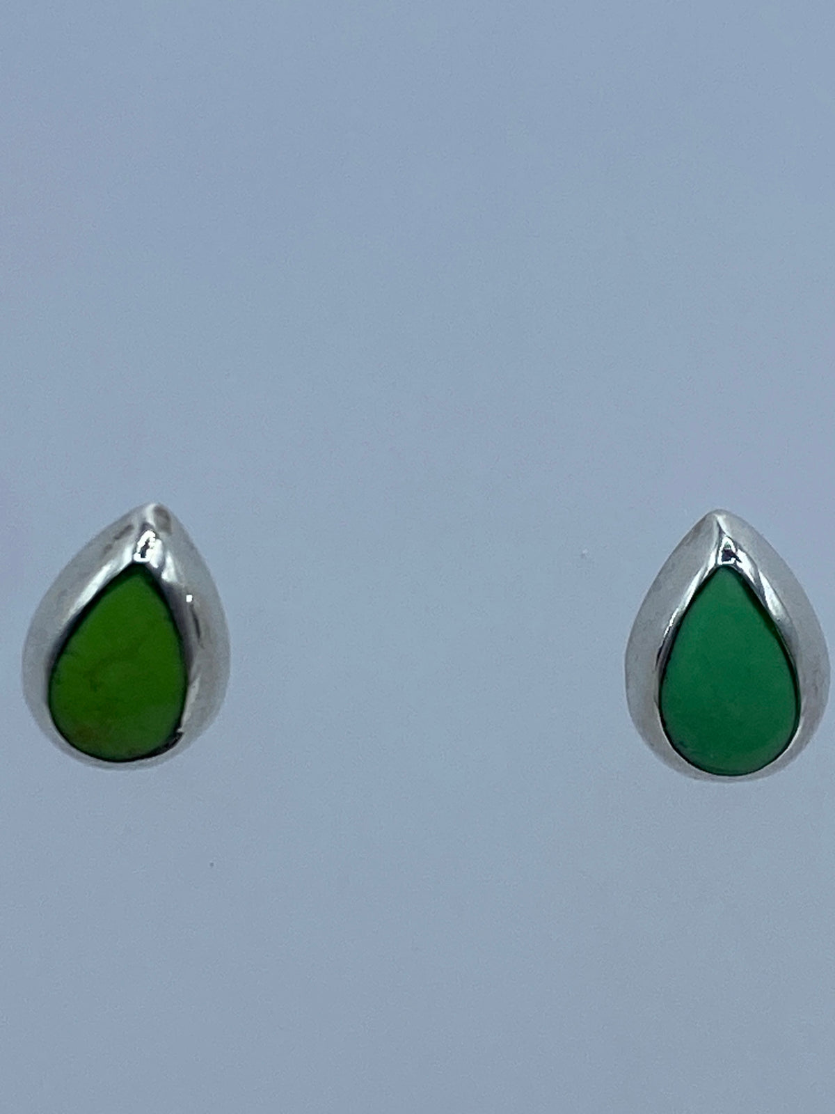 Aretes de plata con piedra verde, detalle lateral mostrando el engaste y el poste