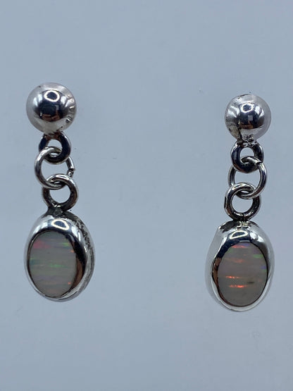 Par de aretes de plata 925 con ópalo de fuego multicolor, largos 2 cm, colgando sobre fondo gris