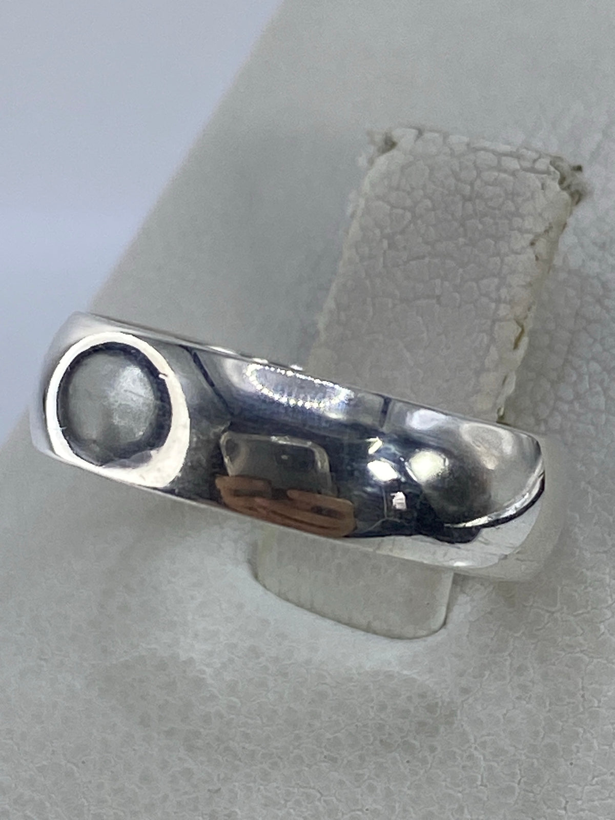 Anillo brillante en plata 925 con acabado pulido, vista lateral sobre papel texturado