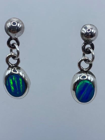 Detalle lateral de los aretes mostrando el brillo azul del ópalo y el engaste de plata