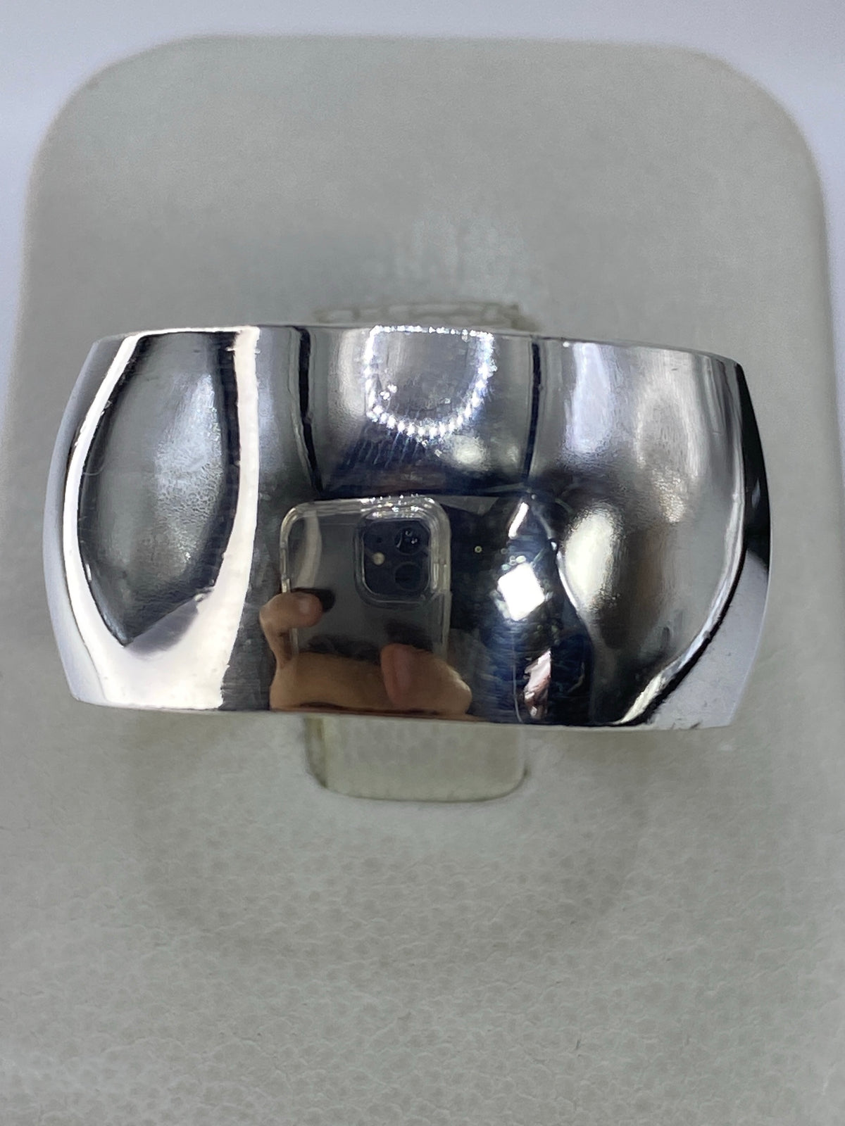 Anillo de plata macizo banda ancha en la mano, mostrando el pulido brillante