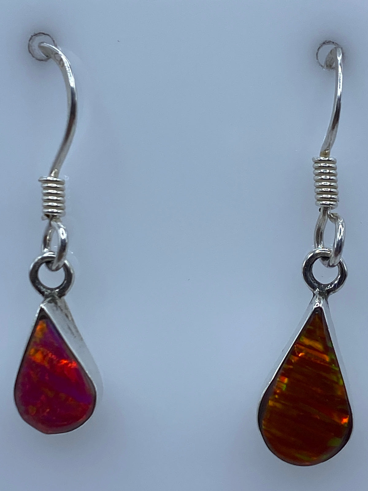 Aretes de plata ópalo de fuego sobre regla de medición mostrando 2.7 cm de largo