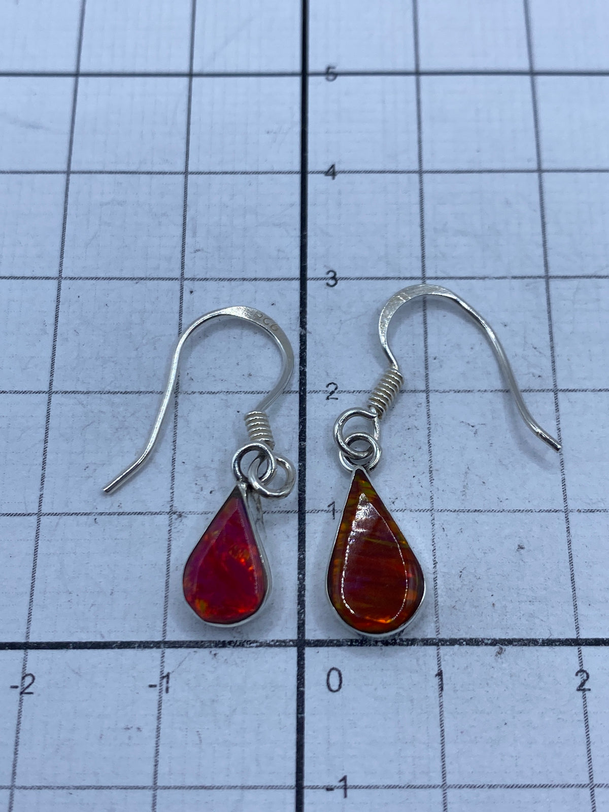 Aretes puestos en mujer, luz natural resaltando el brillo del ópalo