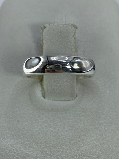 Anillo de plata pulida minimalista en talla 5, visto sobre banda de tela