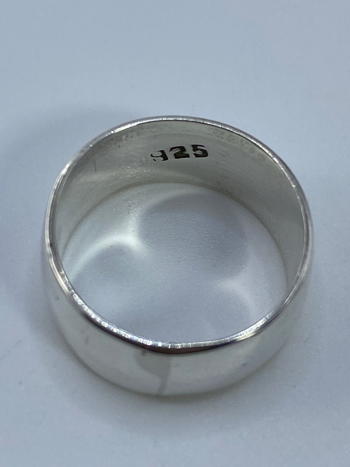 Anillo sobre fondo neutro exhibiendo el brillo de la plata pulida