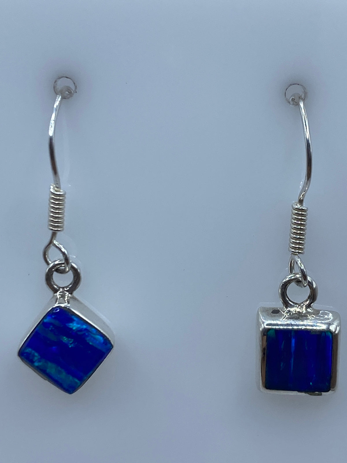 Detalle del ópalo de fuego azul en los aretes, mostrando destellos internos