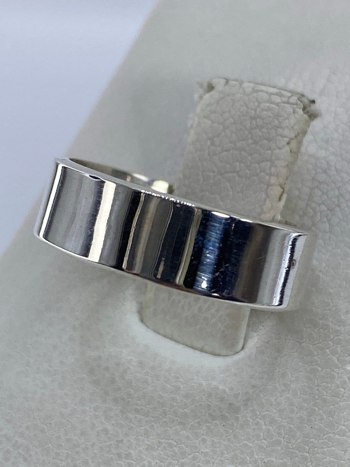 Detalle del anillo plata en la mano, mostrando el espejo brillante
