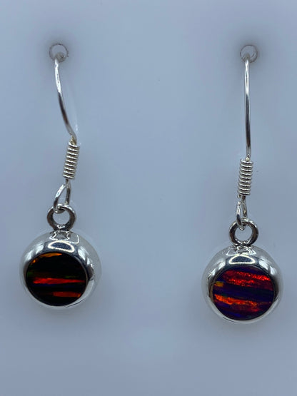 Aretes de ópalo de fuego mostrando los colores rojos y naranjas bajo luz natural