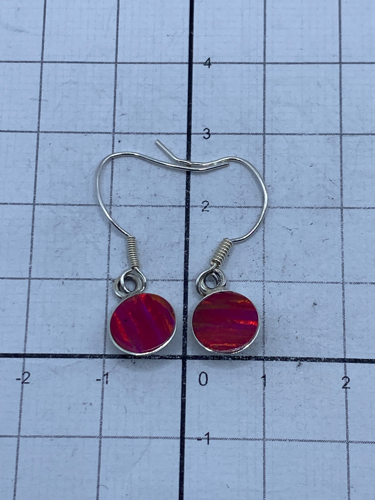 Aretes sobre fondo oscuro resaltando el color rosa fuego