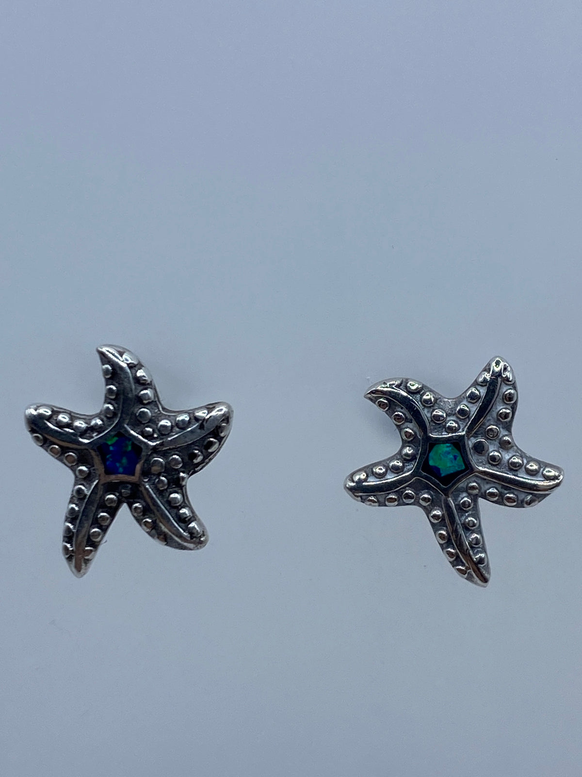 Par de aretes de plata con ópalo de fuego azul sobre fondo gris