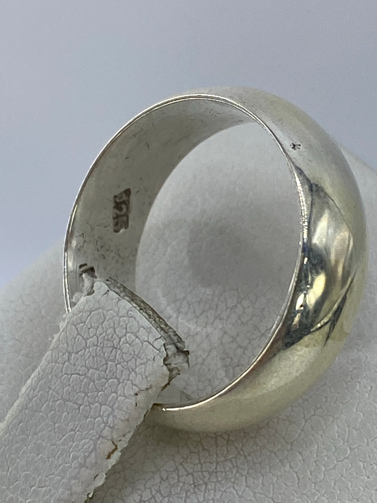 Anillo de plata clásico en la mano, mostrando su brillo