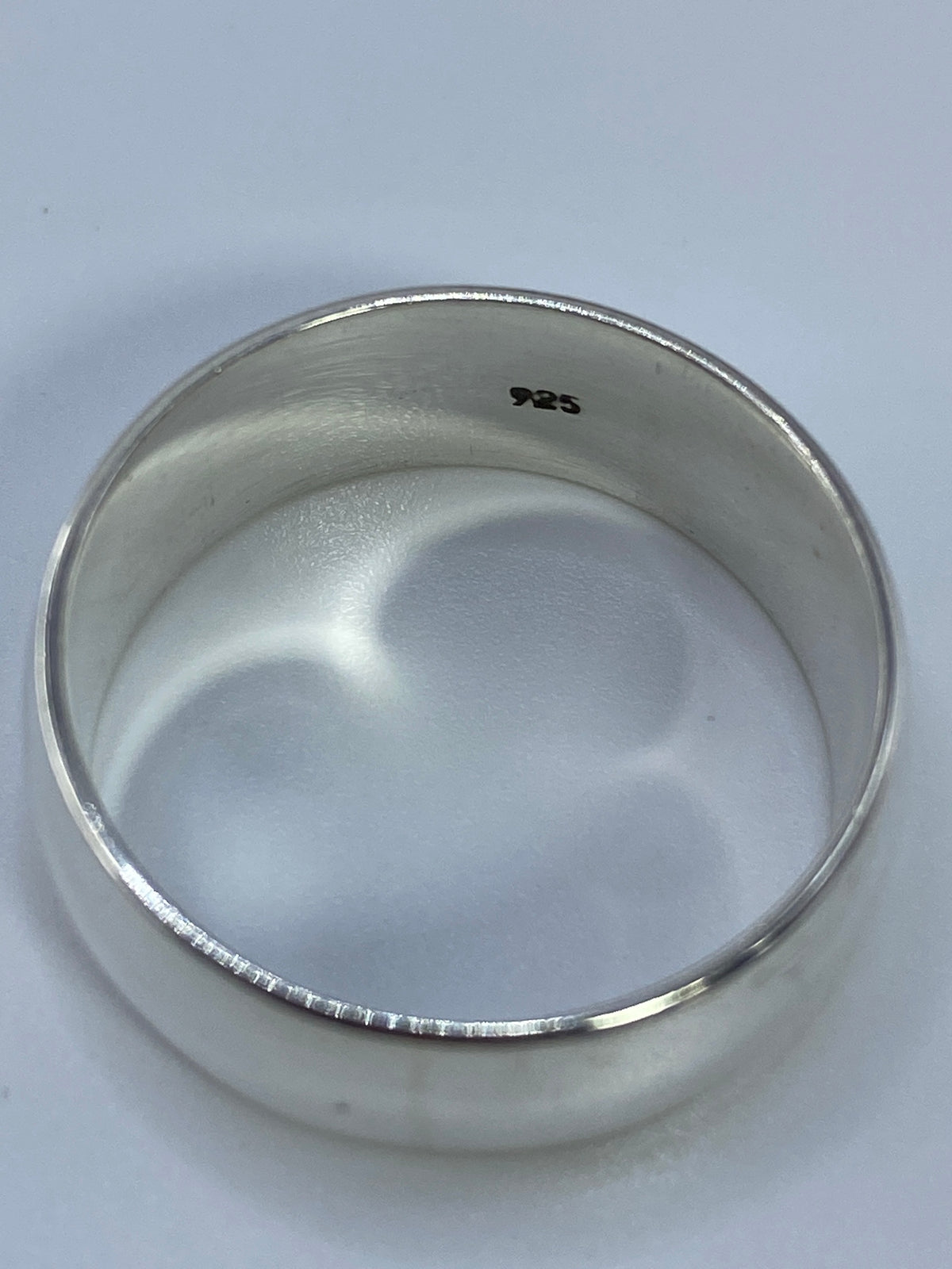 Anillo de plata banda en fondo blanco mostrando el acabado espejo