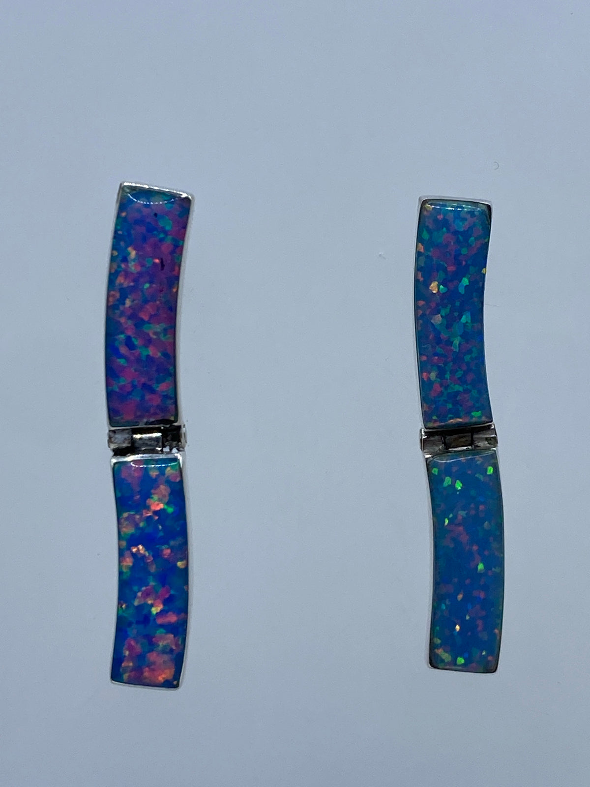 Par de aretes de plata 950 con ópalo de fuego azul, vistos de frente sobre fondo blanco