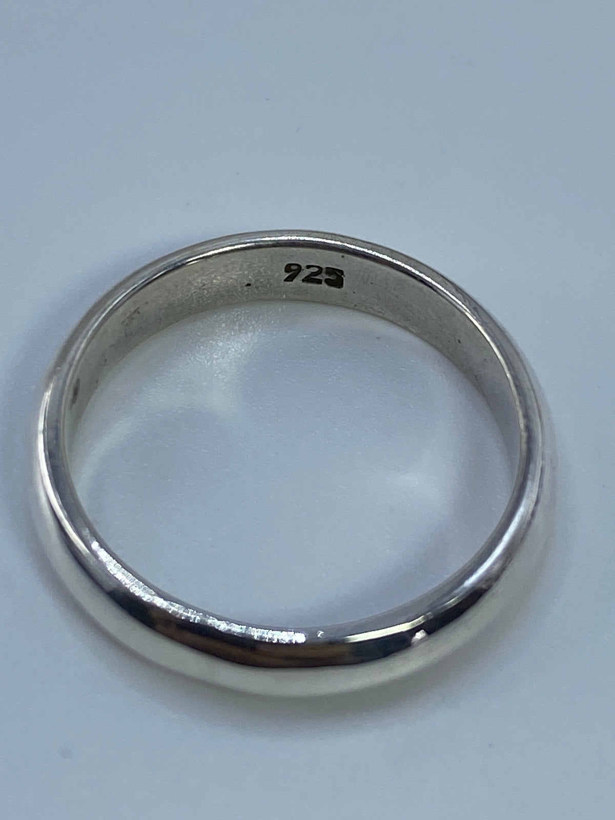 Anillo de banda lisa de plata 925 sobre fondo blanco, vista de perfil