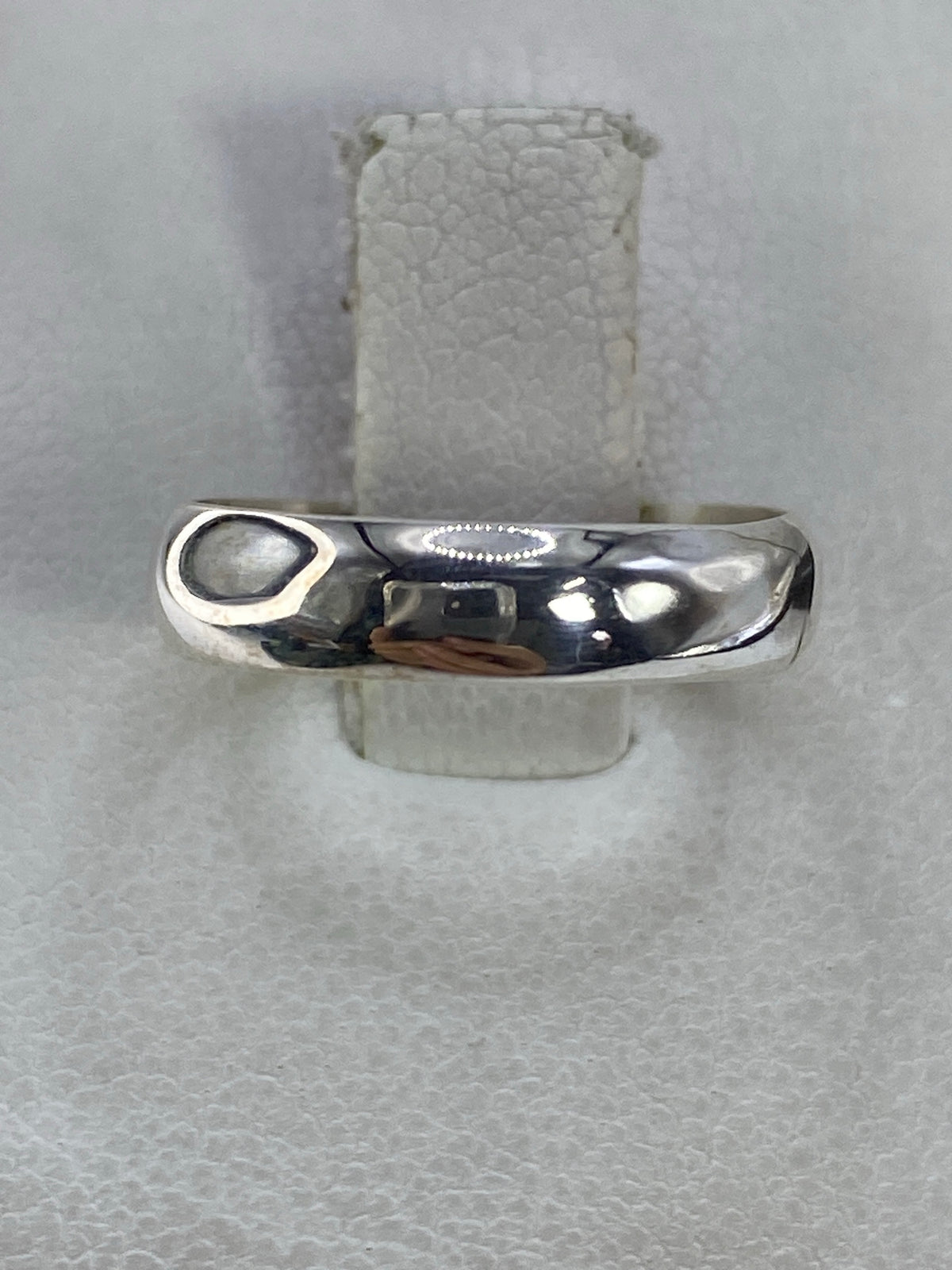 Anillo de plata pulida minimalista en la mano de una mujer