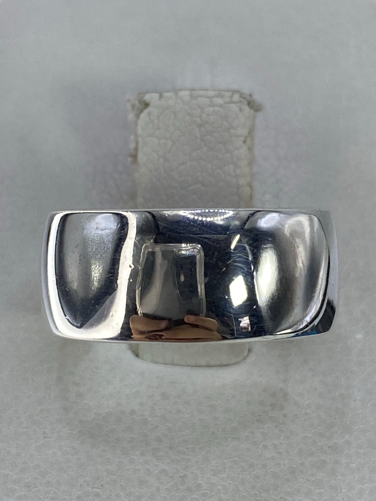 Anillo de plata lisa 925 sobre fondo gris, vista frontal del pulido espejo